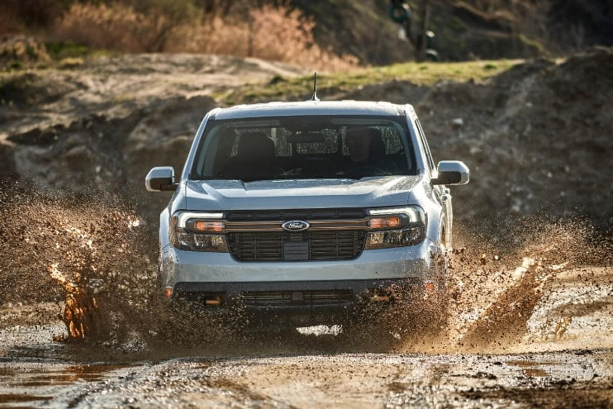 The Ford Maverick Tremor pickup truck is driving through mud.