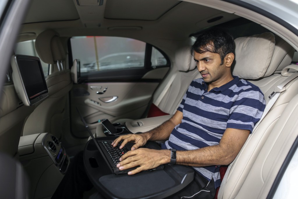 A man uses his laptop in a car with a Wi-Fi signal.