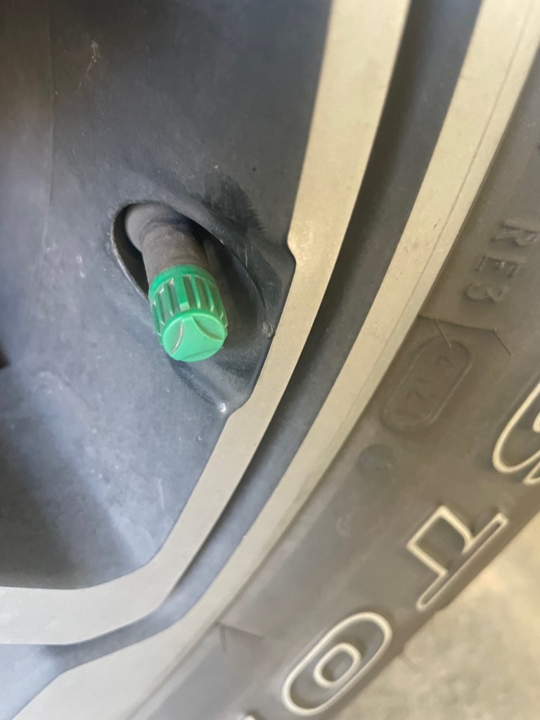 A green valve cap on a truck tire