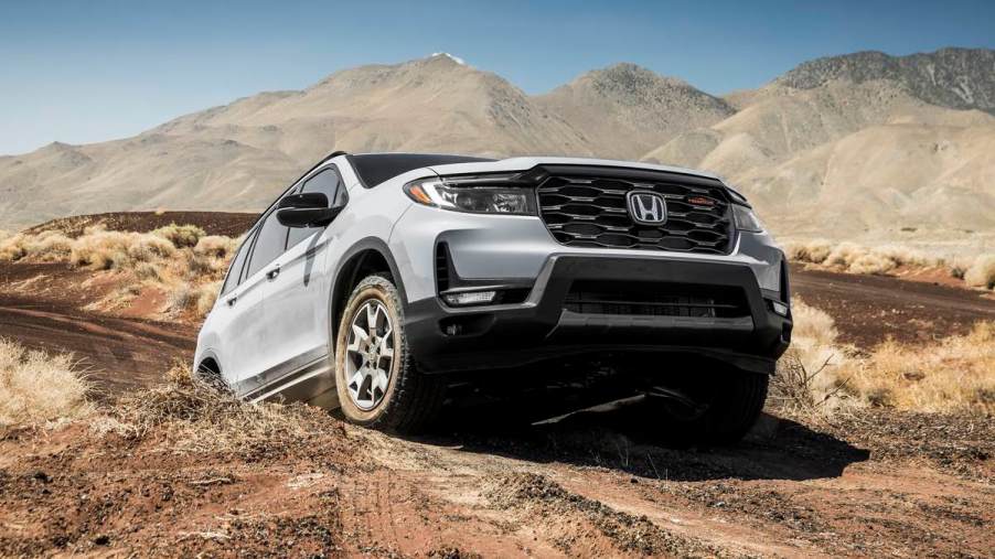 The 2023 Honda Passport TrailSport climbs an off-road obstacle in a desert landscape.