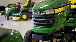 A series of fuel-injected EFI John Deere riding lawn mowers show off their green paintwork.