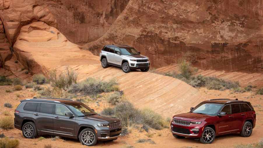 Three different Jeep Grand Cherokee models sit amid red rock formations.