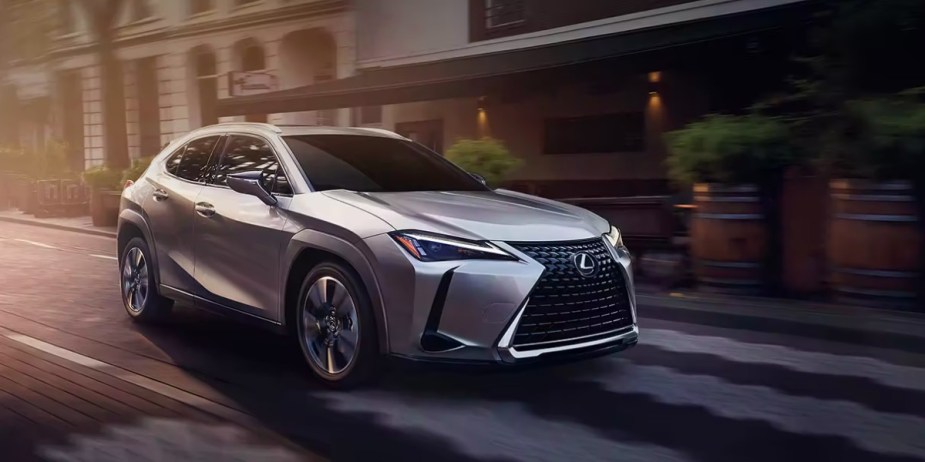 A gray 2023 Lexus UX subcompact SUV is driving on the road. 