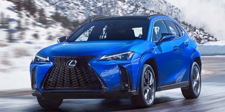 A blue 2023 Lexus UX luxury subcompact SUV is driving on the road. 