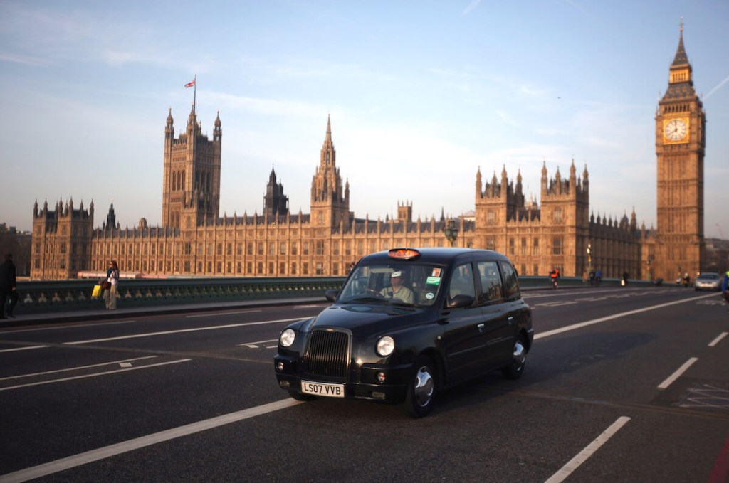 A London Black Taxi driving with the Big Ben in the background