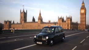 A London Black Taxi driving with the Big Ben in the background