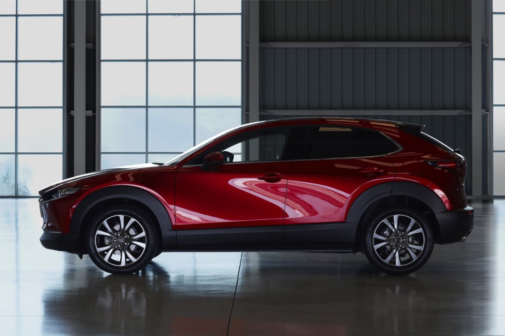 Side view of a red 2023 Mazda CX-30 with high contrast and windows in the background. 