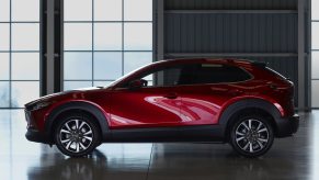 Side view of a red 2023 Mazda CX-30 with high contrast and windows in the background.