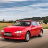 A red Mazda MX-3 driving through the country