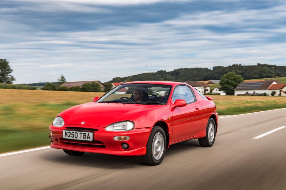 A red Mazda MX-3 driving through the country