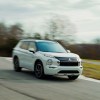 A white 2023 Mitsubishi Outlander PHEV, a great plug-in hybrid SUV for families, drives vigorously.