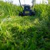 A lawn mower sits in tall grass after mowing a short distance.