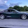 A Mystichrome Ford Mustang Cobra driving down the road
