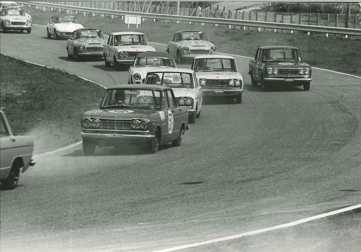 A black and white photo of a Nissan Skyline GT on a racetrack, which is powered by a Gloria V6 engine