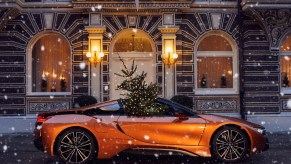 An orange BMW i8 Roadster with a Christmas tree in the passenger seat