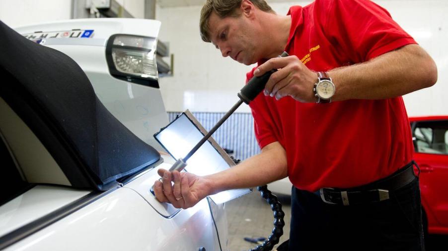 A PDR specialist removes dents from the panels on a car
