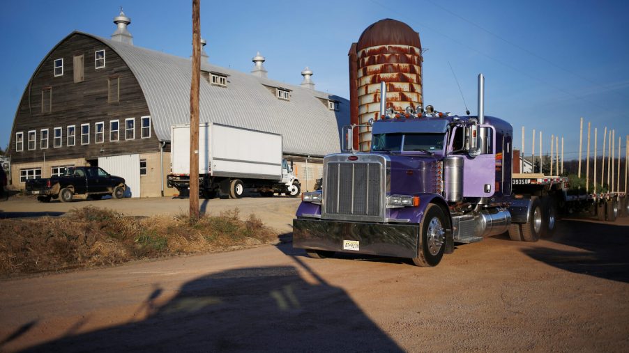 A semi-truck with Pennsylvania plates parked in front of a barn and silo.