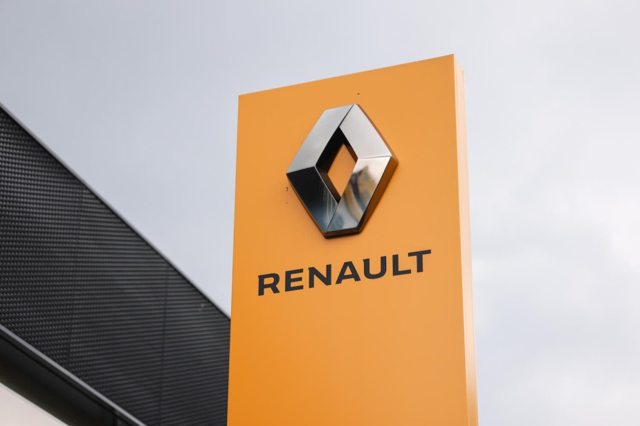The yellow and chrome Renault logo on a sign above a car dealership.