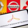 Cellphone with the Renault-Nissan-Mitsubishi Alliance logo with Renault, Nissan, and Mitsubishi's individual logos visible in the background.