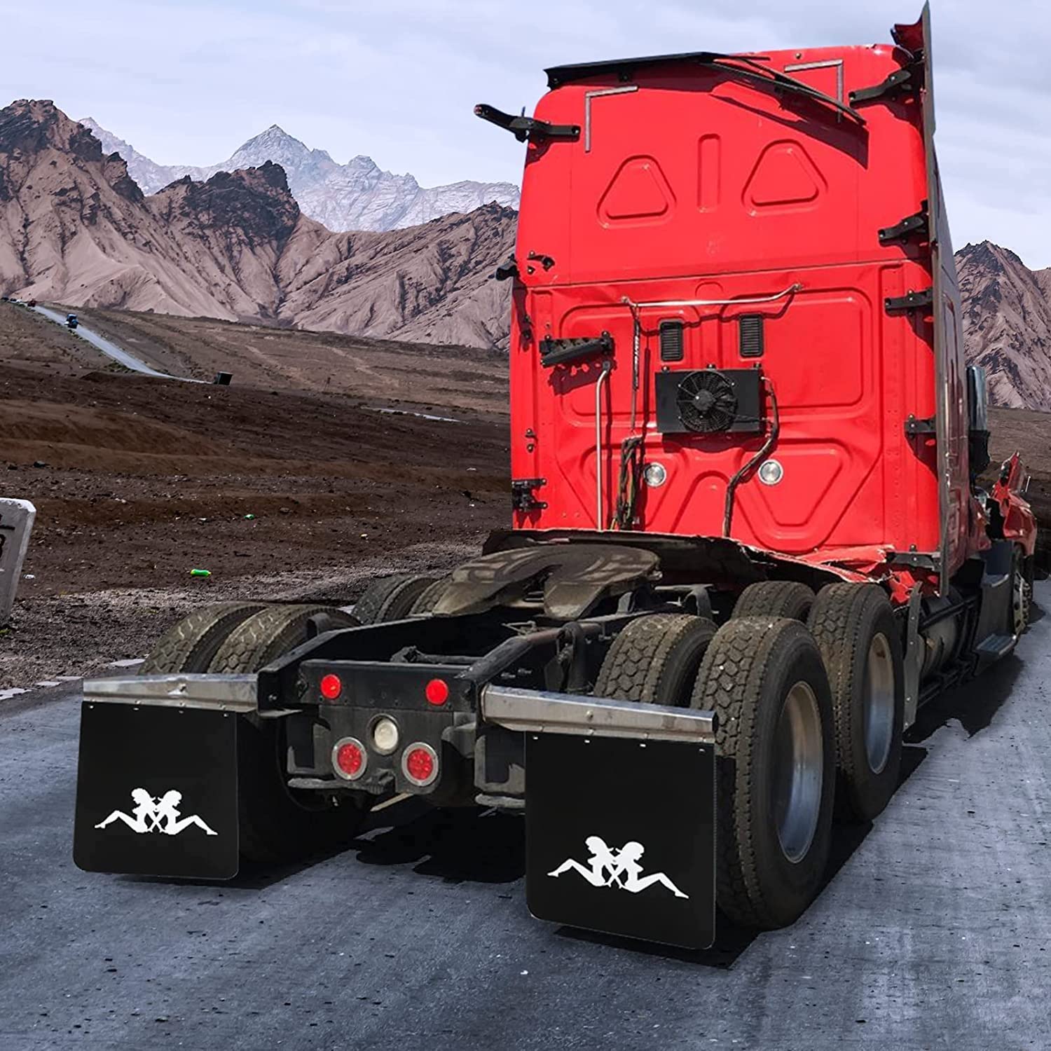 The back of a red semi-truck parked in front of a mountain range with the silhouette of a girl visible on its mudflaps.