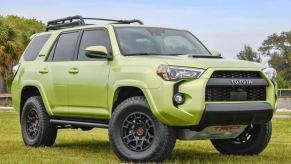 A green Toyota 4Runner TRD Pro sits on a grass field. This 4Runner has an aftermarket supercharger installed on its engine.