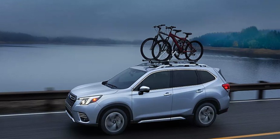 A blue 2023 Subaru Forester is driving on the road. 