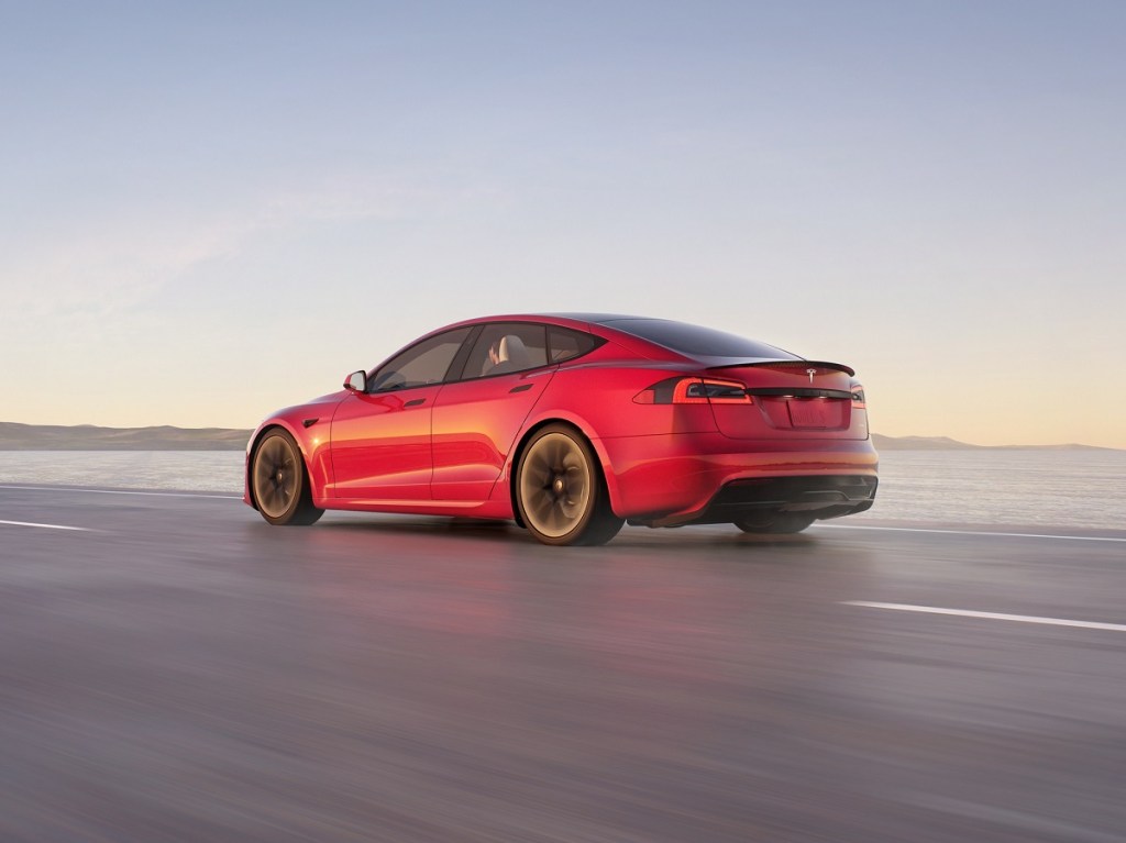 A red Tesla Model S blasts across a slick surface.