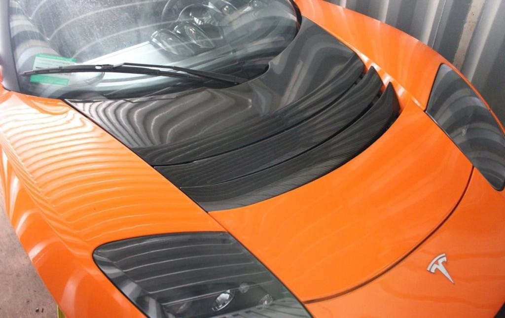 The hood of an orange Tesla Roadster