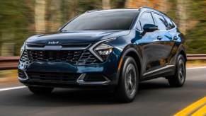 A blue 2023 Kia Sportage Hybrid small hybrid SUV is driving on the road.