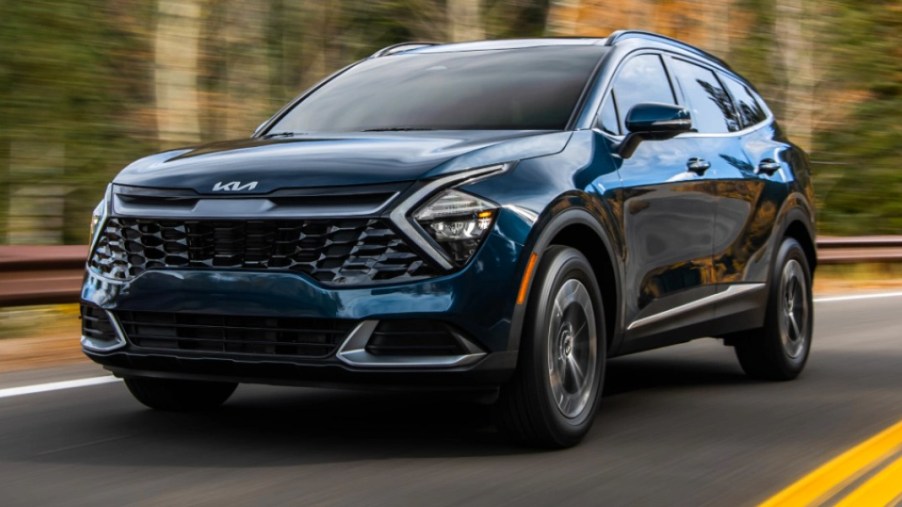 A blue 2023 Kia Sportage Hybrid small hybrid SUV is driving on the road.