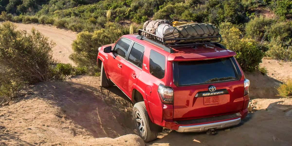 A red 2023 Toyota 4Runner midsize SUV is driving off-road.