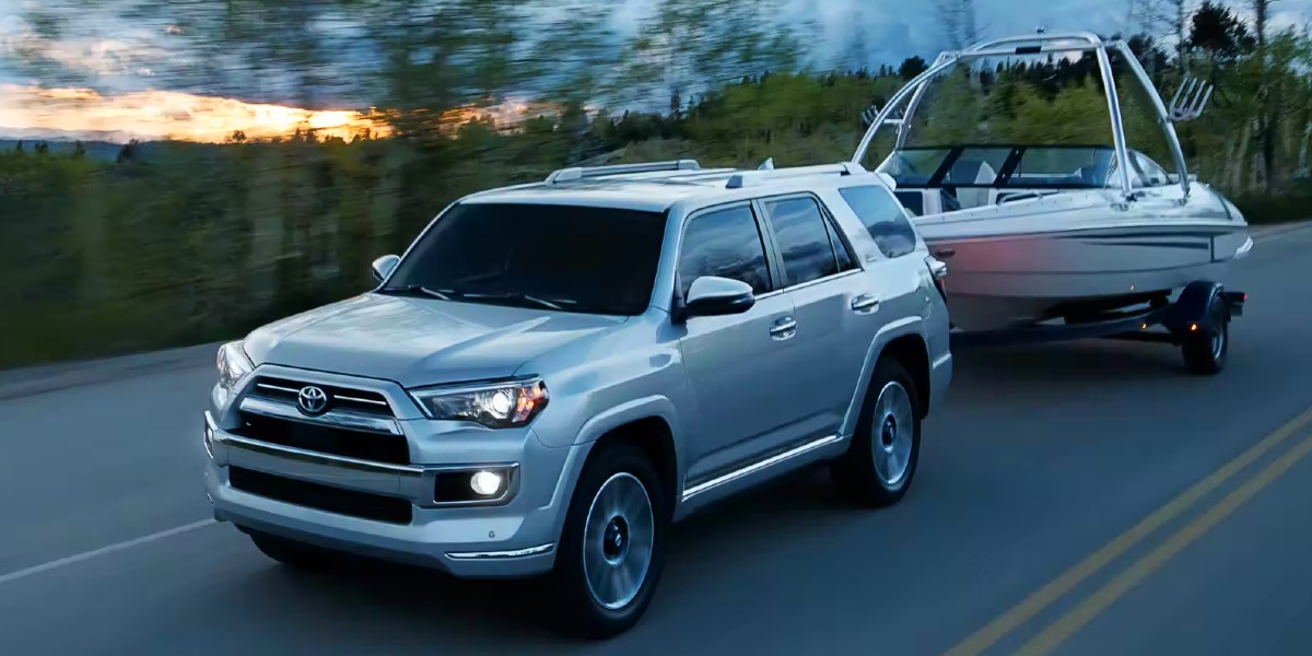 A gray 2023 Toyota 4Runner midsize SUV is towing a boat on the road.