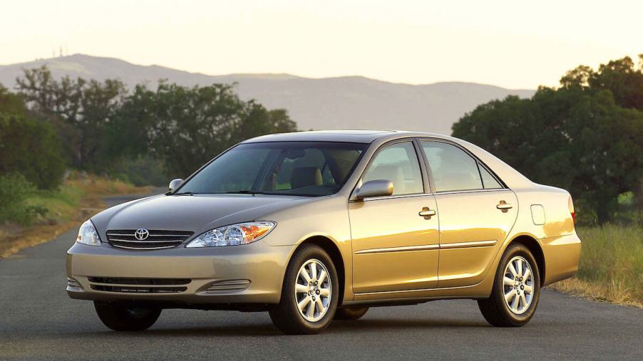 A gold Toyota Camry parked on a single lane road at sunset