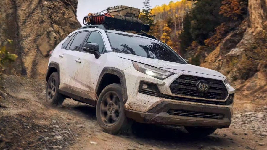 A white 2023 Toyota RAV4 small SUV is driving off-road.