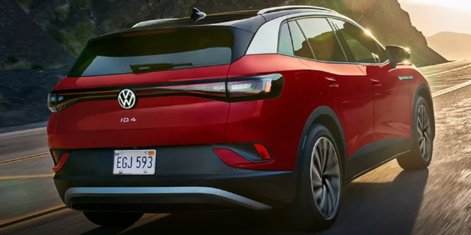 A red 2023 Volkswagen ID.4 small electric SUV is driving on the road. 