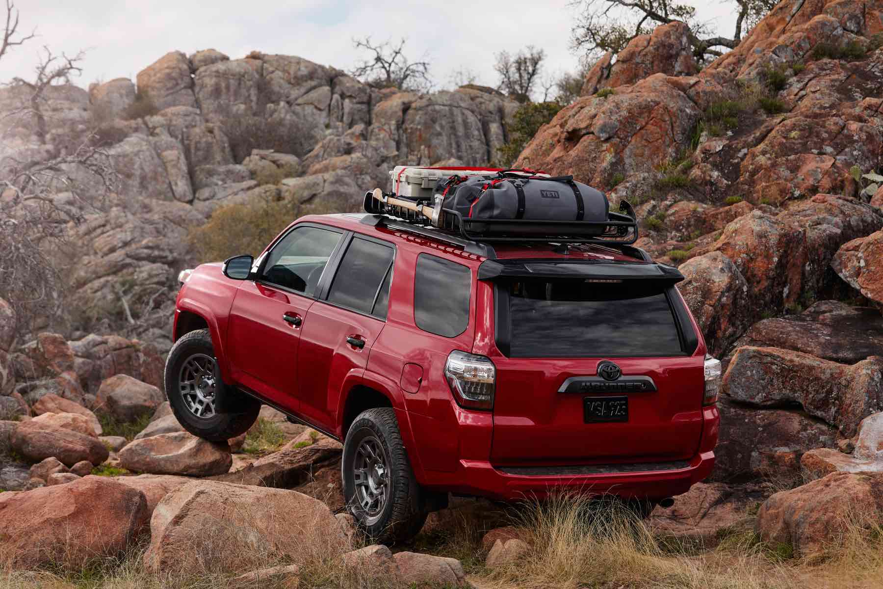 A red Toyota 4Runner climbs up a rocky slope. The 4Runner is the Toyota's closest model to the Lexus GX.