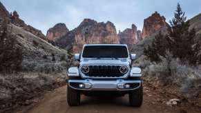 A Wrangler 4xe drives on a trail with a dramatic desert mountain scenery in the background. Jeep claims a Wrangler EV is on the way in years ahead.