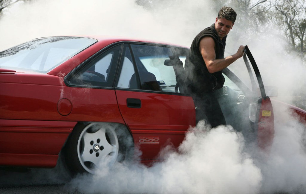 A car enthusiast does a burnout in an old Ford Focus