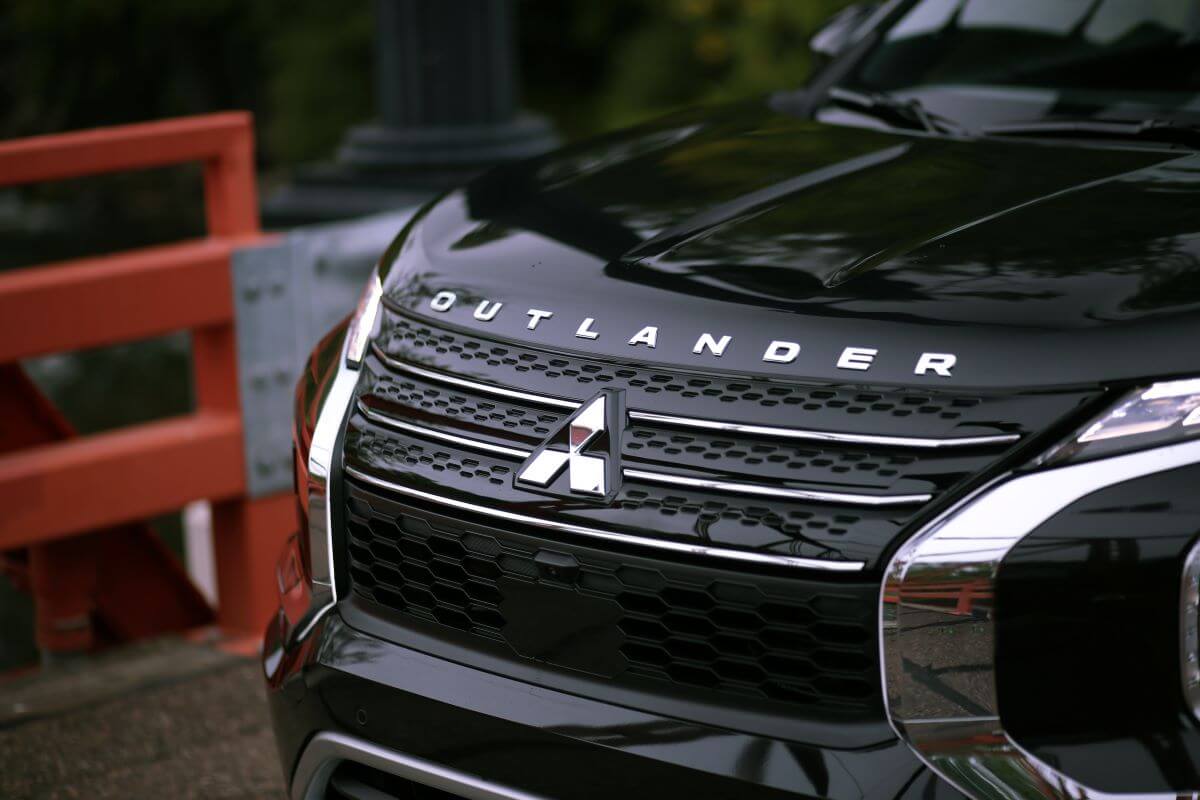 The grille, logo, and badging on the front of a black 2023 Mitsubishi Outlander PHEV compact crossover SUV model