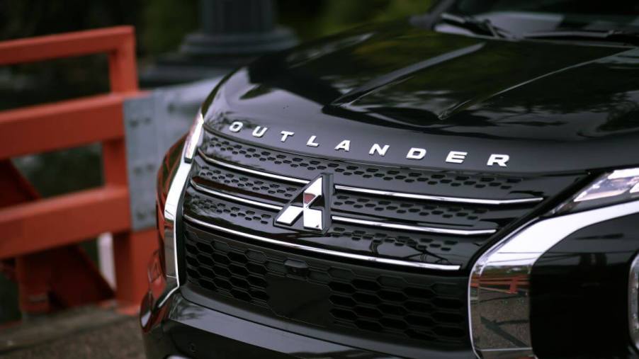 The grille, logo, and badging on the front of a black 2023 Mitsubishi Outlander PHEV compact crossover SUV model
