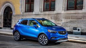 A blue 2019 Buick Encore subcompact SUV model parked outside an old brick building