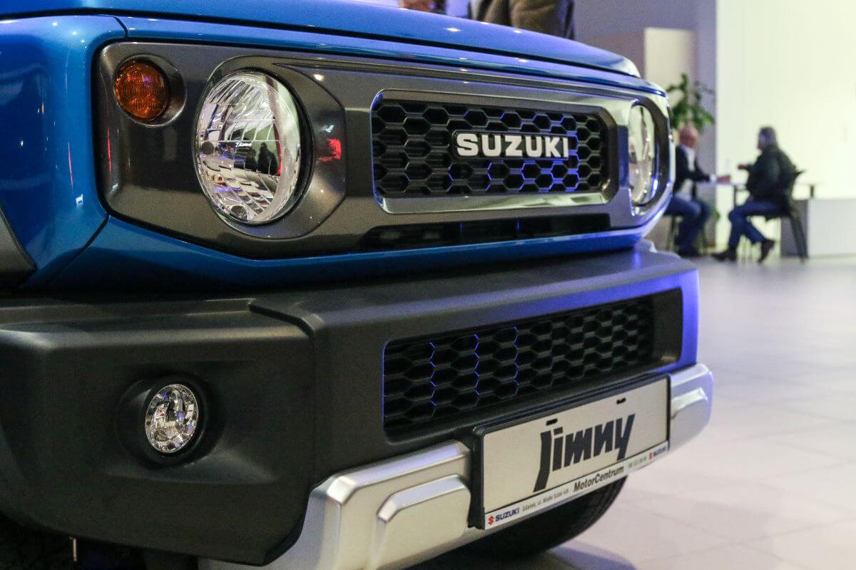 A blue Suzuki Jimny off-road SUV model on display with make and model nameplate front badging
