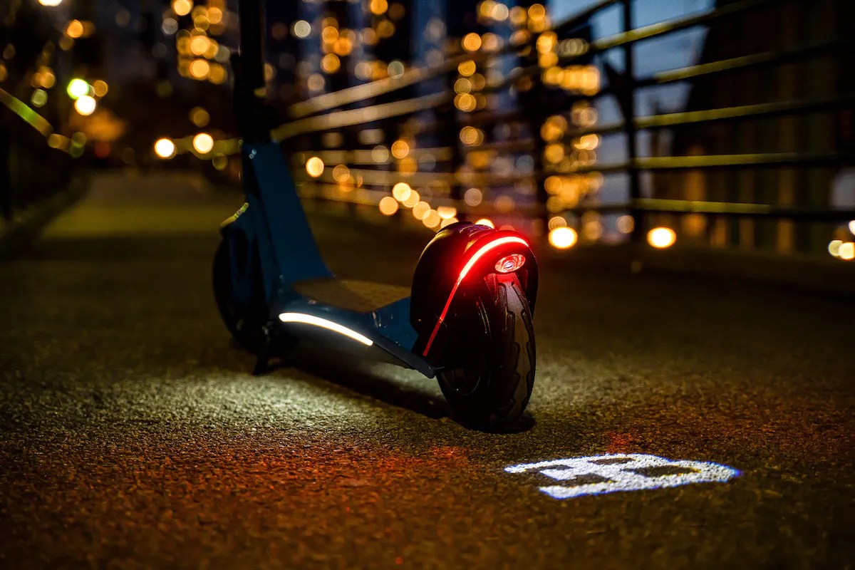 A Costco Bugatti scooter showing its taillights at night.