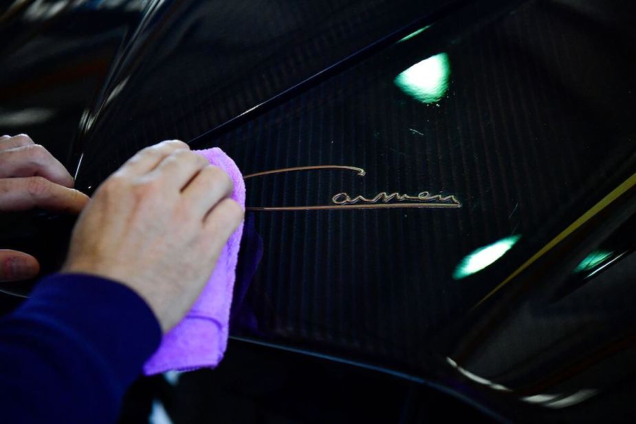 A man uses a towel to clean a car