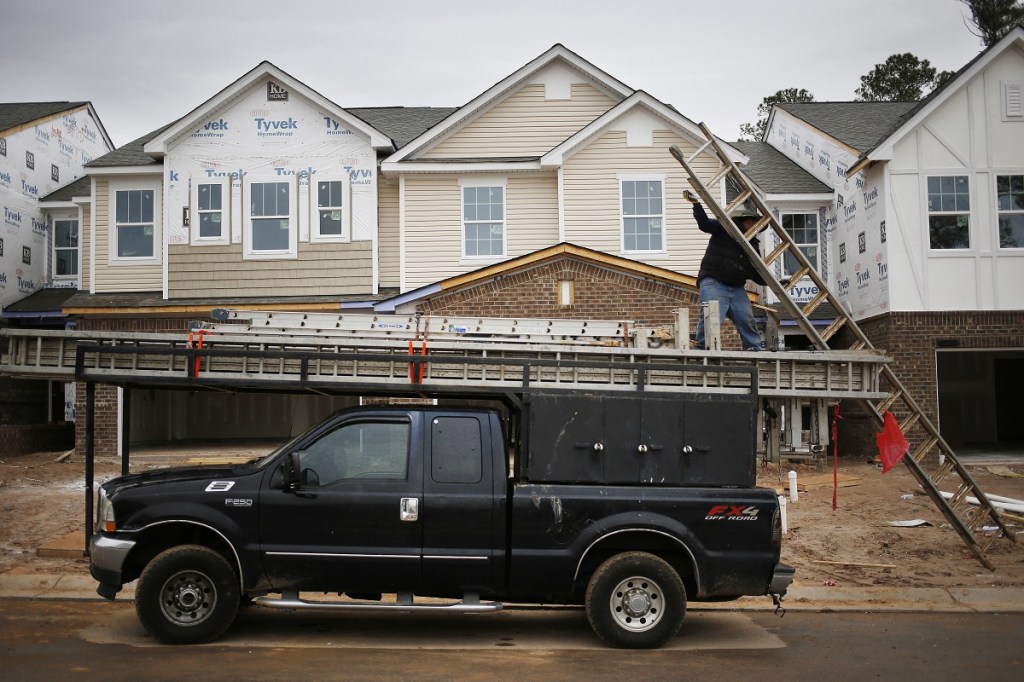 A construction workers lowers a ladder from his truck