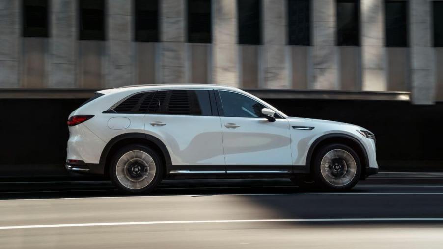 An exterior side shot of a white 2024 Mazda CX-90 PHEV full-size SUV model driving