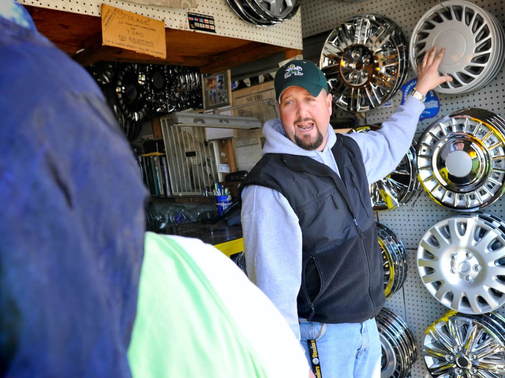A hubcap shop owner talks to a customer.