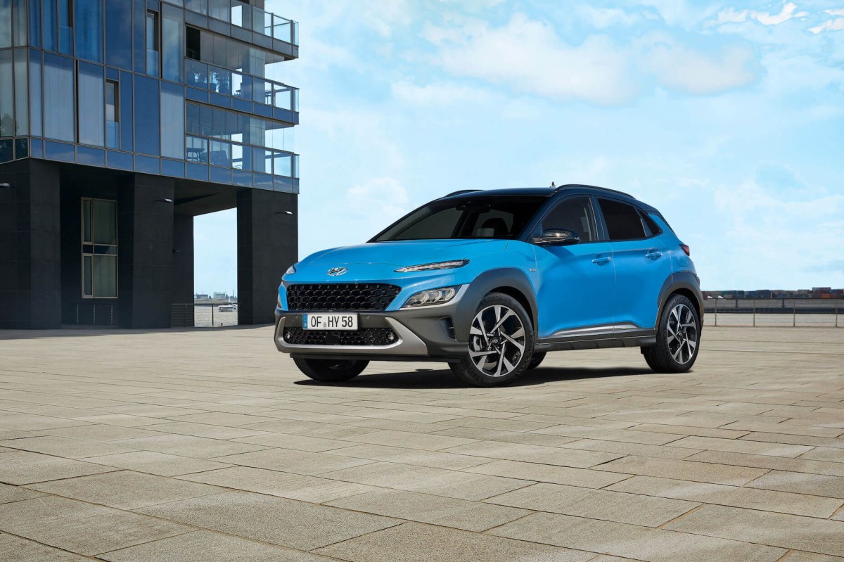 A blue 2023 Hyundai Kona located outside a modern building with blue skies in the background.