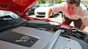 A sales manager at a dealership inspects the engine on a Nissan 350Z