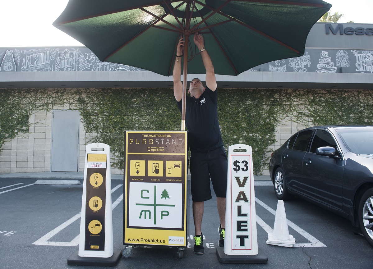 A parking lot valet opens his umbrella
